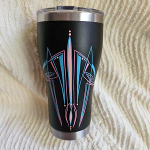 May include: Black stainless steel tumbler with a pink and blue pinstripe design. The design features a stylized flame pattern.