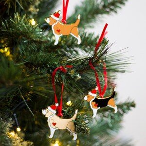 Puede incluir: Tres adornos navide&ntilde;os con forma de perros que llevan gorros de Pap&aacute; Noel. Los adornos est&aacute;n hechos de metal y tienen un acabado dorado. Los perros son de diferentes razas y colores, incluyendo un perro marr&oacute;n y blanco, un perro negro y blanco y un perro crema.