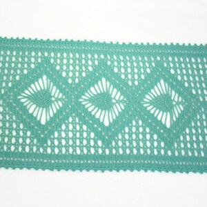 May include: A teal crocheted table runner with a delicate diamond pattern and floral accents.