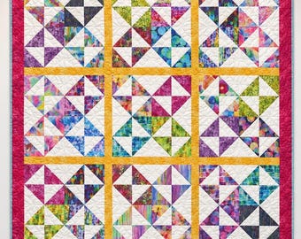 May include: A square quilt featuring a grid of nine blocks, each composed of four smaller triangle-based squares. The blocks are separated by yellow sashing and framed by a wide, textured hot pink border with a light blue edge trim.
