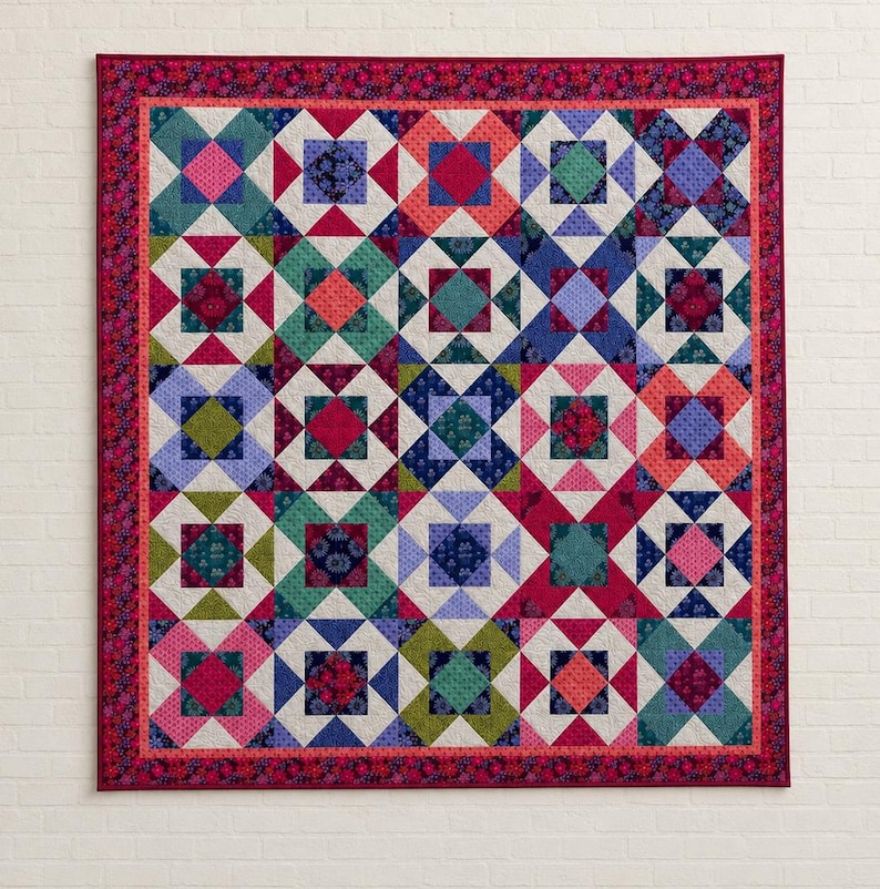 May include: A square quilt featuring a repeating geometric block pattern composed of various floral and solid fabric squares in shades of pink, teal, blue, green, and orange, finished with a dark red floral border and a thin pink inner border.