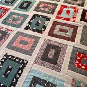 May include: A patchwork quilt featuring a repeating log cabin block pattern. The quilt is composed of various fabric squares in shades of red, blue, black, grey, and white, with floral, bird, and geometric prints separated by white sashing strips.