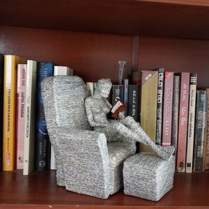 Donna che legge seduta su una comoda sedia, scultura in cartapesta,