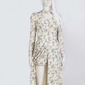 May include: A long white dress with a floral pattern. The dress has a high neckline and long sleeves. The dress is made of a lightweight fabric and has a flowing silhouette.