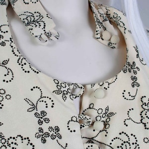 May include: A white blouse with a black floral pattern and a button-up front. The collar is a separate piece that can be worn up or down.