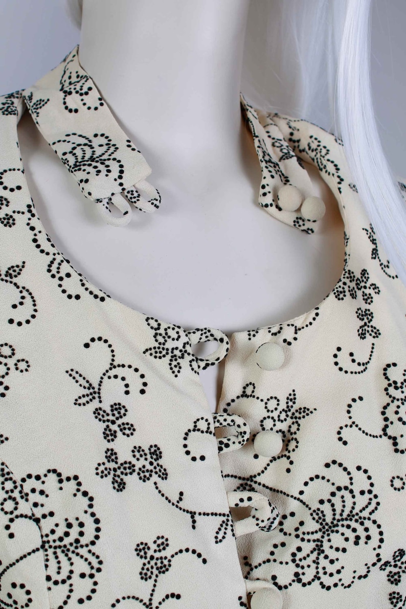 May include: A white blouse with a black floral pattern and a button-up front. The collar is a separate piece that can be worn up or down.