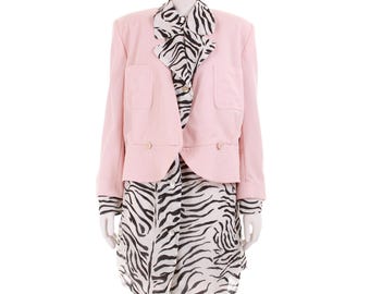 Puede incluir: Un blazer rosa claro con dos bolsillos delanteros y dos botones, combinado con un vestido con estampado de cebra y una camisa con cuello con estampado de cebra. El conjunto se exhibe en un maniquí.