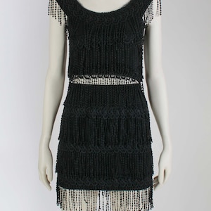 May include: A black mini dress with a layered fringe design. The dress has a scoop neckline and short sleeves.
