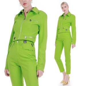 May include: A lime green two-piece outfit consisting of a cropped jacket and high-waisted pants. The jacket has a zipper closure and multiple pockets. The pants have a straight leg fit.