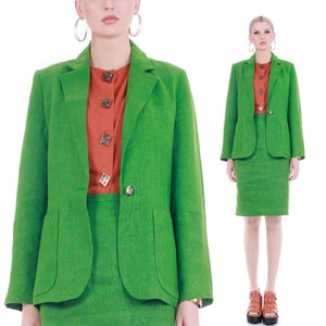 May include: A green linen blazer and skirt suit. The blazer has a single button closure and flap pockets. The skirt is a pencil skirt.