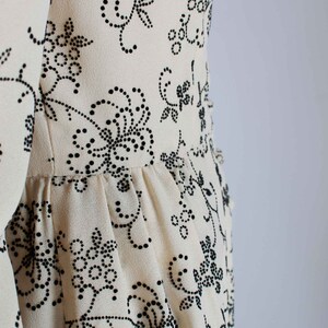 May include: A white dress with a black floral pattern. The dress has a fitted bodice and a flowing skirt.