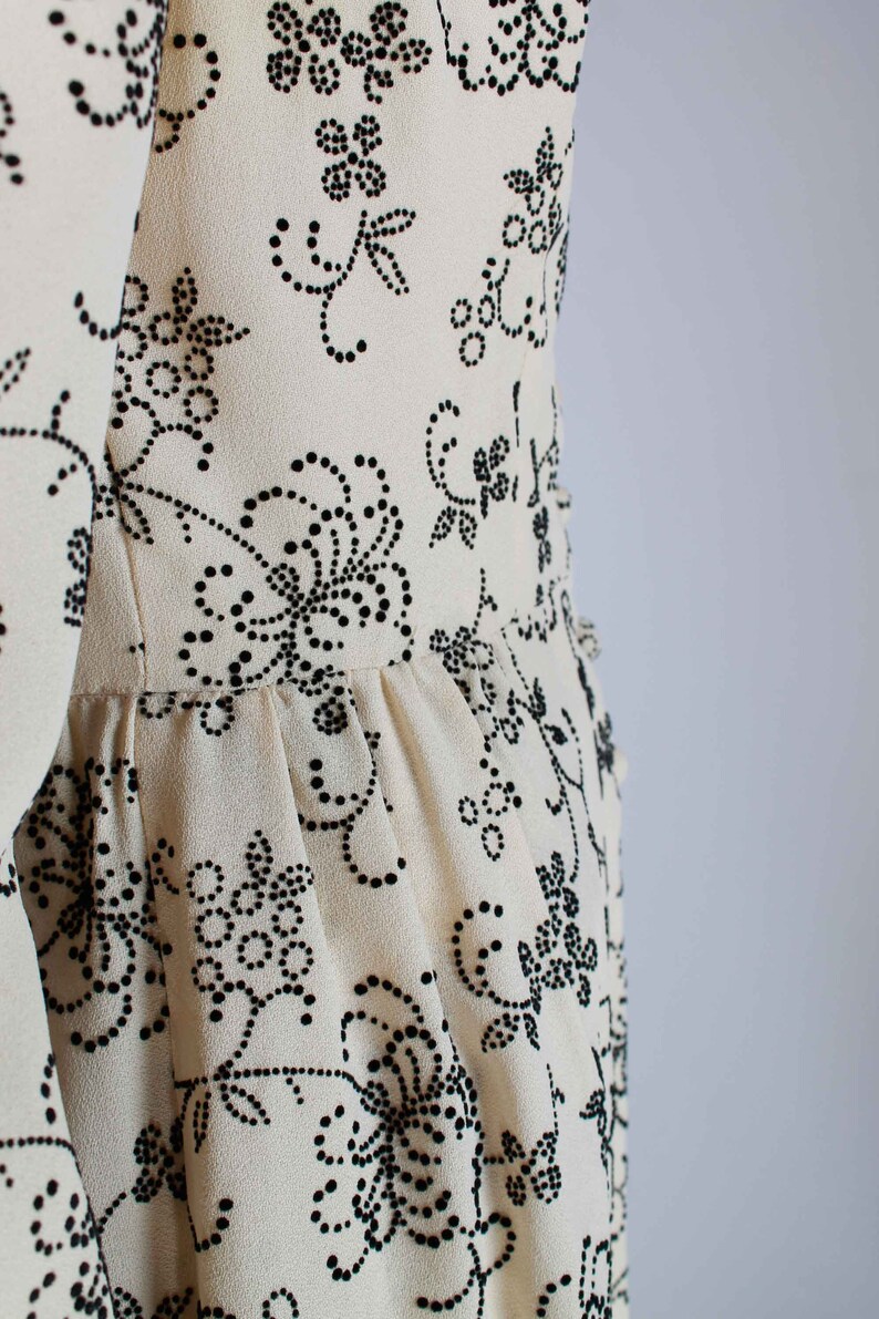 May include: A white dress with a black floral pattern. The dress has a fitted bodice and a flowing skirt.
