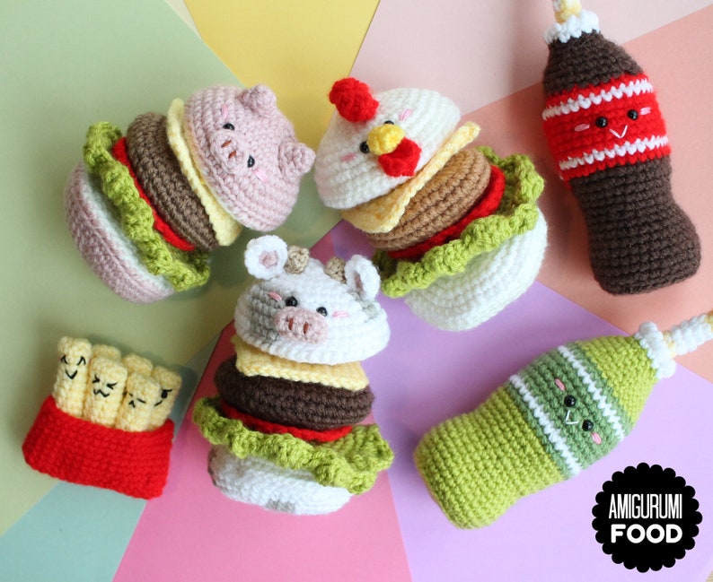 May include: A collection of crocheted amigurumi food items including three animal-themed burgers, a red container of fries with faces, and two beverage bottles with faces. The text AMIGURUMI FOOD is printed in white on a black scalloped circular badge.