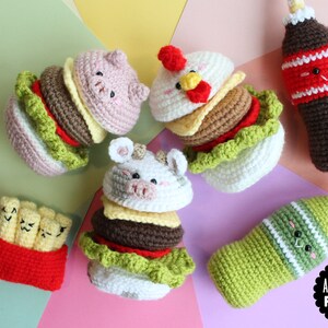 May include: A collection of crocheted amigurumi food items including three animal-themed burgers, a container of french fries, and two beverage bottles. Each item features embroidered facial expressions. A black logo reads AMIGURUMI FOOD.