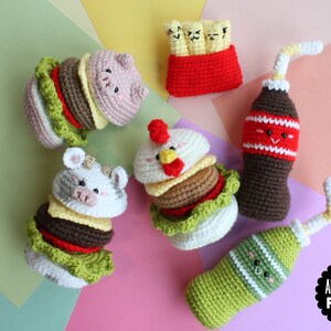 May include: A collection of crocheted food items including two animal-themed burgers, a container of fries with faces, and two bottles with straws and faces. The items feature various colors like brown, green, red, white, and yellow. Text reads AMIGURUMI FOOD.