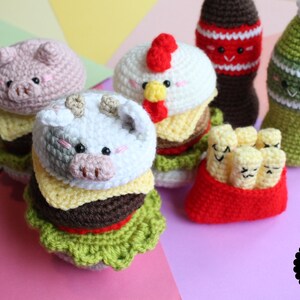 May include: A collection of crocheted amigurumi food items including two animal-themed burgers, a red container of french fries, and two beverage bottles. Each item features embroidered facial expressions. A black circular logo reads AMIGURUMI FOOD.