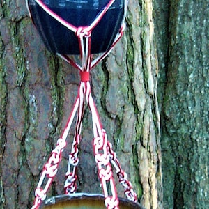 Puede incluir: Dos macetas colgantes de cerámica azul y marrón con cuerda de macramé blanca y roja.