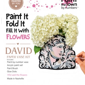 Könnte beinhalten: Ein Paint the Town by numbers David Papier-Vasen-Set mit einer flachen, ausgeschnittenen Vase mit bemaltem Büstenmotiv, gefüllt mit weißen Hortensien. Das Set enthält eine Malen-nach-Zahlen-Vase, Acrylfarben, einen Pinsel und Klebepunkte.