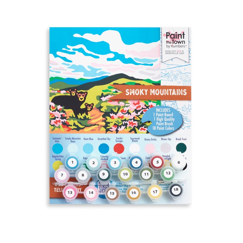 A black bear family stands on top of a mountain grassland surrounded by flowering shrubs such as azalea and rhododendron.  The skies are full of colorful clouds, and the image also shows the colorful paint strips and paint brush that come with each kit.