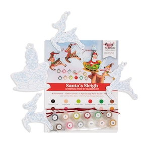 Könnte beinhalten: Ein Malen-nach-Zahlen-Set mit vier Weihnachtsanhängern: Weihnachtsmann im Schlitten, zwei Rentiere und ein Rentier, das den Schlitten zieht. Das Set enthält 12 Farben, einen Pinsel und Anweisungen. "Paint the Town by Numbers" ist auf der Schachtel aufgedruckt.