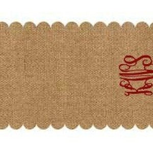 May include: A brown burlap table runner with a scalloped edge and a red monogram "SMW" in the bottom right corner.