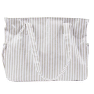 Peut inclure: Un sac cabas rayé beige et blanc avec deux anses. Le sac est fait d'un matériau doux, semblable à une toile.