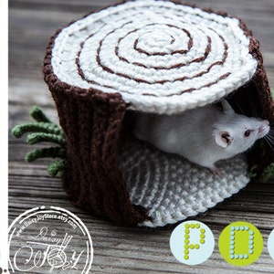 May include: A crocheted log cabin with a white and brown color scheme, featuring a small white mouse peeking out from the opening. The log cabin is a handmade pet bed for small animals.