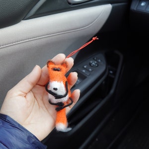 May include: A small orange and white fox plush toy with black eyes and a black nose. The fox is holding its paws together and has a long, fluffy tail.