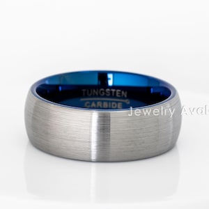 Peut inclure: Une bague en carbure de tungst&egrave;ne argent&eacute; avec une finition bross&eacute;e et un int&eacute;rieur bleu vif. La bague porte l'inscription "Tungsten Carbide" &agrave; l'int&eacute;rieur. Jewelry Avalanche est imprim&eacute; sur le c&ocirc;t&eacute;.