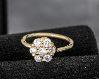 Può includere: Un anello per il naso in oro con una montatura a forma di fiore di pietre di zircone cubico trasparenti.