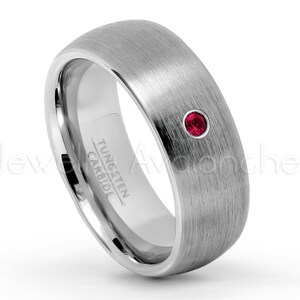 Könnte beinhalten: Ein silberner Wolframkarbidring mit gebürsteter Oberfläche. Der Ring hat einen einzelnen, runden, roten Edelstein. Die Worte "Tungsten Carbide" sind auf der Innenseite des Rings eingraviert.