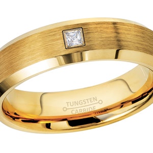 Op de afbeelding: Een gouden ring van wolframcarbide met een geborstelde afwerking en een enkele vierkante diamant. De ring is gegraveerd met "TUNGSTEN CARBIDE".