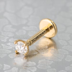 May include: A gold nose stud with a clear round gemstone.