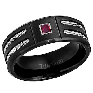 Puede incluir: Anillo de titanio negro con una piedra roja y un diseño de cable. El anillo está grabado con la palabra "Titanium".