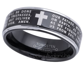 Peut inclure: Bague noire en carbure de tungstène avec une croix argentée et du texte gravé. La bague présente la prière du Seigneur et les mots "Tungstène Carbure" et "Jewelry Avalanche". Un accessoire religieux.