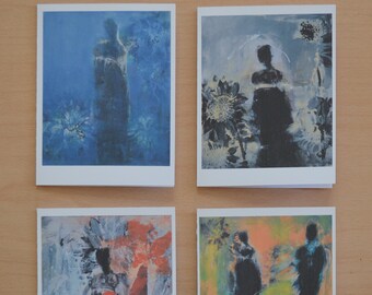 May include: Four art cards with abstract paintings. Each card features a figure in silhouette against a backdrop of blues, oranges, and greens. The cards are displayed on a light brown wooden surface.