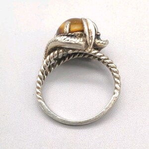 May include: A silver ring with a brown tiger's eye stone set in a twisted band.