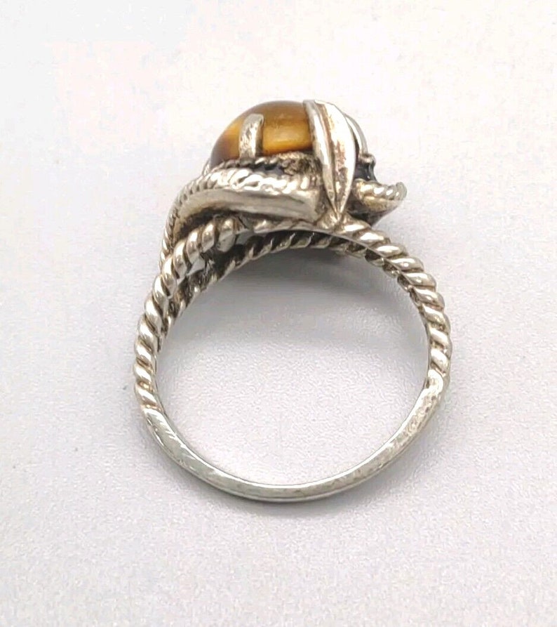 May include: A silver ring with a brown tiger's eye stone set in a twisted band.