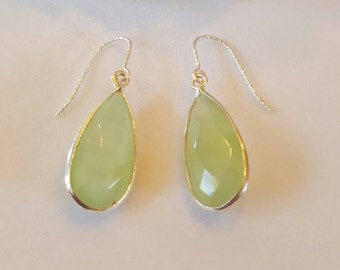 Puede incluir: Un par de pendientes de plata en forma de lágrima con gotas de piedras preciosas verde claro.