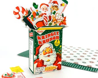 May include: A vintage-style Christmas-themed box of "Kringle Krunch" cereal, featuring Santa Claus illustrations. The box is green and red, with additional Christmas-themed cutouts and stickers scattered around. The box contains 1/4 oz or 21.3 grams of cereal.