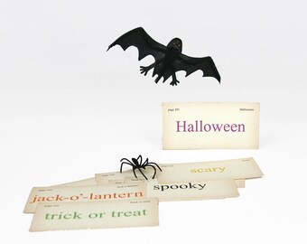 May include: A black bat and spider Halloween decorations with a stack of cards that say "Halloween", "scary", "spooky", "jack-o'-lantern", and "trick or treat".