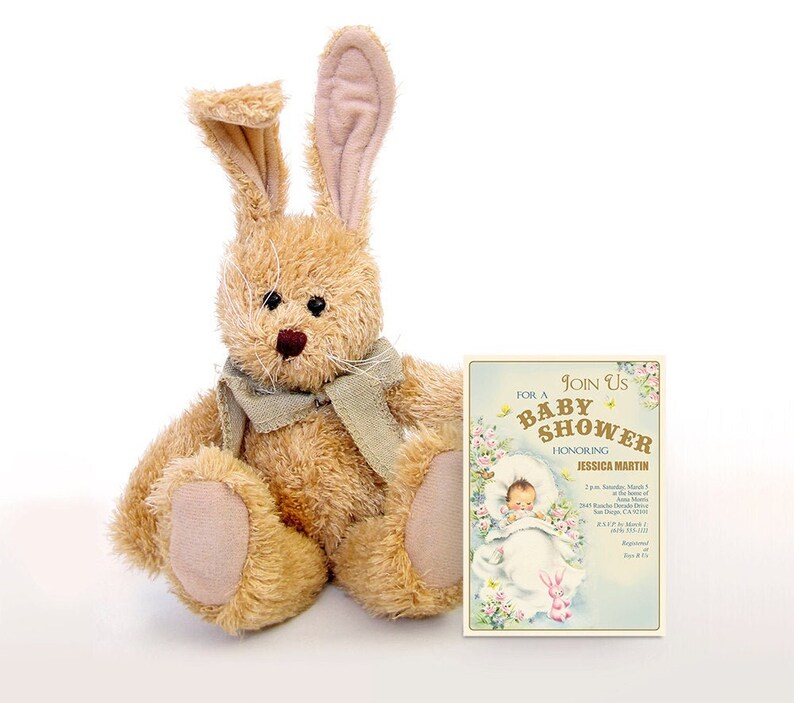 Puede incluir: Un conejito de peluche marr&oacute;n con una bufanda gris se sienta junto a una invitaci&oacute;n a un baby shower. La invitaci&oacute;n es para Jessica Martin y presenta a un beb&eacute; en una manta blanca con un conejito rosa. La invitaci&oacute;n incluye la fecha, la hora y la ubicaci&oacute;n de la ducha.
