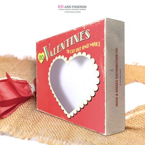 May include: A red box with a white heart cutout and the text "20 Valentines to cut out and make" and "Hugs & Kisses Distribution Co."