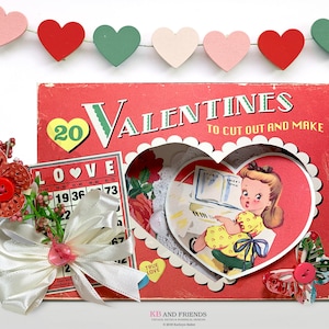 May include: A vintage Valentine's Day craft kit with a red cover and the text "20 Valentines to cut out and make". The kit includes a heart-shaped cutout with a girl playing the piano, a love bingo card, and a white satin ribbon bow.