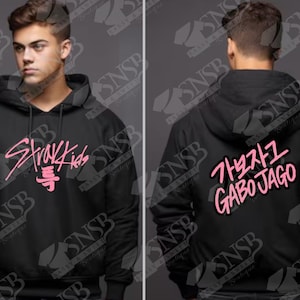 以下が含まれることがあります： 前面にピンク色の「Stray Kids」の文字、背面に韓国語のテキストと「GABO JAGO」がプリントされた黒いパーカー。 ドローストリングフードとフロントポケットが付いています。