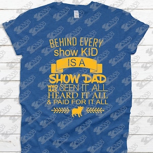 May include: A blue t-shirt with the text "Behind every show kid is a show dad who seen it all heard it all & paid for it all" in yellow. A small pig illustration is below the text.
