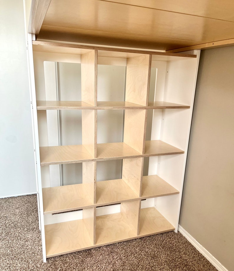 May include: A white shelf unit with 12 square compartments. The shelves are made of light wood and are empty.
