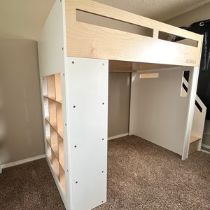 May include: White loft bed with a built-in bookshelf and a ladder. The bed frame is made of wood and has a white finish. The bookshelf has multiple shelves and is made of wood with a natural finish. The ladder is made of wood and has a white finish. The bed is in a room with beige carpet.