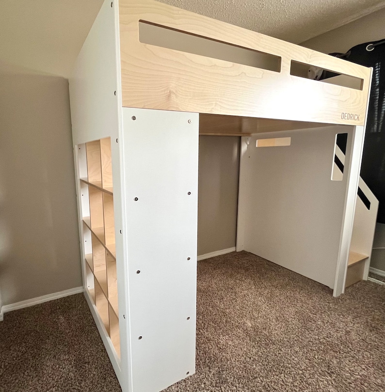 May include: White loft bed with a built-in bookshelf and a ladder. The bed frame is made of wood and has a white finish. The bookshelf has multiple shelves and is made of wood with a natural finish. The ladder is made of wood and has a white finish. The bed is in a room with beige carpet.