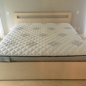 May include: A light wood platform bed frame with a white mattress and a headboard with a rectangular cutout.